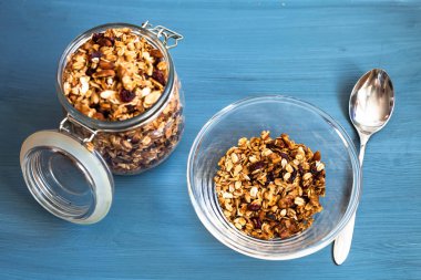 Bir plaka üzerinde bir mavi arka plan, yulaflı müsli, fındık, tohumlar ve kurutulmuş meyve sağlıklı kahvaltı ev yapımı müsli