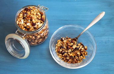 Bir plaka üzerinde bir mavi arka plan, yulaflı müsli, fındık, tohumlar ve kurutulmuş meyve sağlıklı kahvaltı ev yapımı müsli
