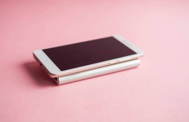 Beyaz akıllı telefon şarj cihazı ile şarj cihazı gücü banka pembe bir arka plan üzerinde