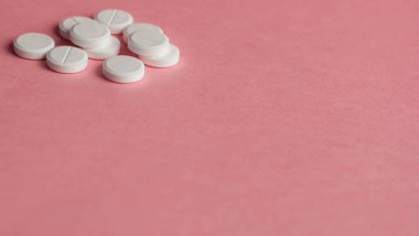 Pembe bir arka plan üzerinde beyaz hap. Soldaki metin için yer.