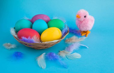 Bir boşaltmak bir mavi renk zemin üzerine sepetteki renkli Paskalya yumurtaları