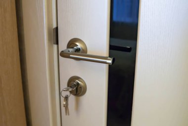 Metal kapı kolu ve anahtarlar yakın çekim. siyah cam lı beyaz kapı