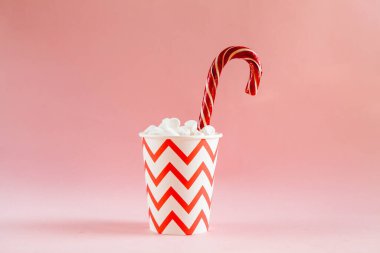 Pembe arka planda şekerlemeli şenlik bardağı. Noel konsepti. Minimalizm.