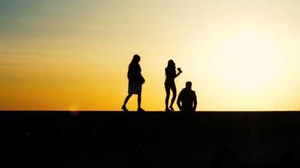 Silhouettes of people in the photo session, the girl is shooting at sunset — Stock Video