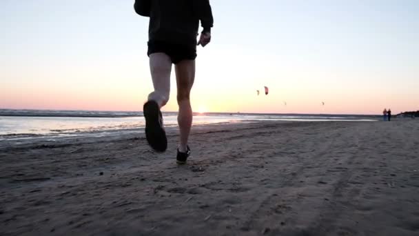 Mann mit aufgeblasenen Kälbern rennt dem Sonnenuntergang auf dem Wasser entgegen, Zeitlupe — Stockvideo