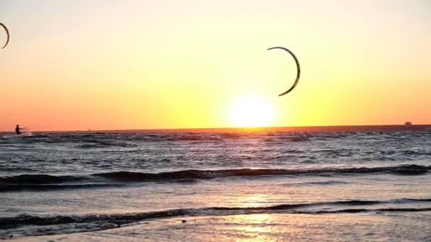 Kitesurfers jezdit na západ slunce pozadí na moři, pomalý pohyb — Stock video