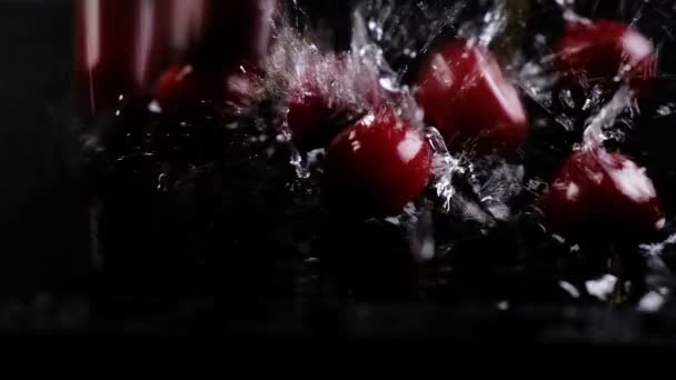 Rijpe kersen berry valt in het water op een donkere achtergrond. Slow motion — Stockvideo