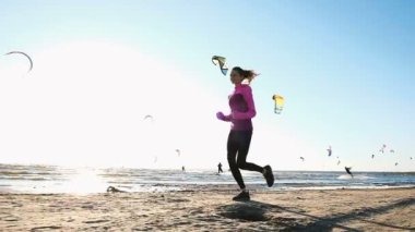 Yaz aylarında sahilde kitesurfers, ağır çekim bir arka plan üzerinde çalışan genç kadın
