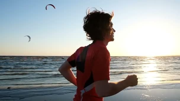 L'uomo felice corre contro il tramonto e finisce, alza le mani e rimbalza, rallenta — Video Stock