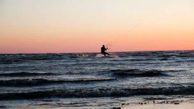 Denize yakın, yaz yavaş hareket içinde gün batımında kitesurfer silüeti