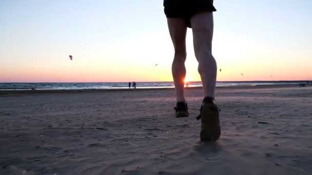 Dmuchany na kawior mężczyzn uruchomić do spełnienia na zachód słońca na piaszczystej plaży, w zwolnionym tempie — Wideo stockowe