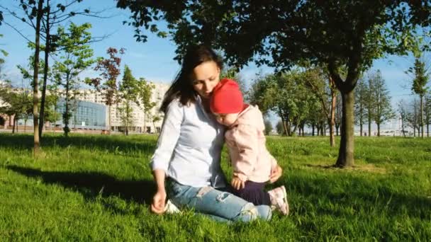 La mujer y el niño juegan en la naturaleza. Alegre madre cosquillas hoja de hierba cara de niño — Vídeo de stock