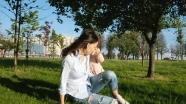 Genç Anne ile bebeği parkta oynarken. Mutlu kadın çocuğun arkasına koyar