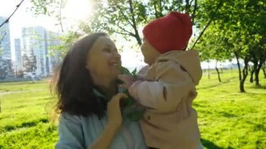 Günbatımında bir şube parkta oynarken mutlu bir aile. Anne bir çocuğun kollarında açık havada tutar.