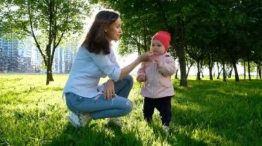 Gün batımında parkta bir çiçek koklama bebek annesiyle. Küçük kızı için kolları annesi ağır çekim sorar..