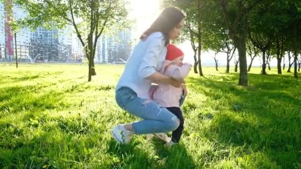 Madre joven caminando con el bebé en el parque al atardecer, cámara lenta . — Vídeos de Stock
