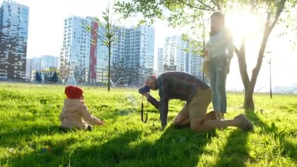 Jonge vader maakt een foto van een jonge dochter in een park bij zonsondergang. Gelukkige familie neemt foto's van een kind in de natuur — Stockvideo