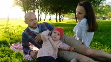 Bir akıllı telefon onun elinde tutan, Evet küçük bebeği. Mutlu aile açık havada yaz gün batımında piknik
