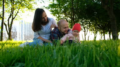 Mutlu aile doğa istirahat ediyor. Veliler bir parkta küçük bebek kızı olan yaz aylarında günbatımı, kamera hareketi oynayan