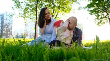 Mutlu aile doğa istirahat ediyor. Veliler bir parkta küçük çocuk kızı olan yaz aylarında günbatımında oynayan.