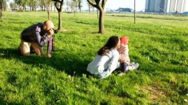 Genç Baba öpüşme anne ve kızı parkta batımında fotoğraf çekme. Mutlu aile doğada fotoğraf çekmek
