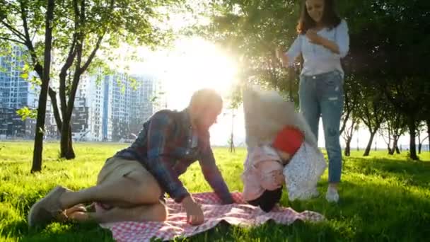 Familia feliz en un picnic con un niño descansando en la naturaleza al atardecer en el parque . — Vídeo de stock