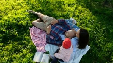 Mutlu aile çarptırılmış döşeme ve selfie bir bebekle günbatımında parkta yapıyor. Baba ve anne bebek, kamera hareketi ile kendilerini fotoğraf çekmek