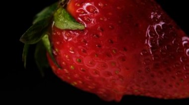 Su akar çilek yakın siyah bir arka plan yavaş hareket aşağı