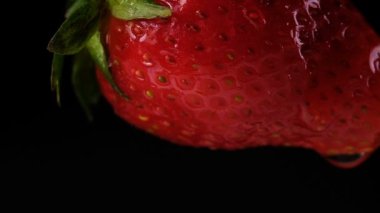 Sallanan, ağır çekim bir siyah arka plan üzerine çilek yakın çekim. Berry aşağı su akar