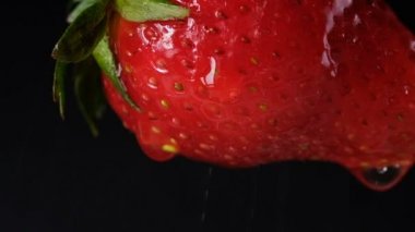 Sallanan, ağır çekim karanlık bir arka plan üzerinde çilek yakın çekim. Berry aşağı su akar