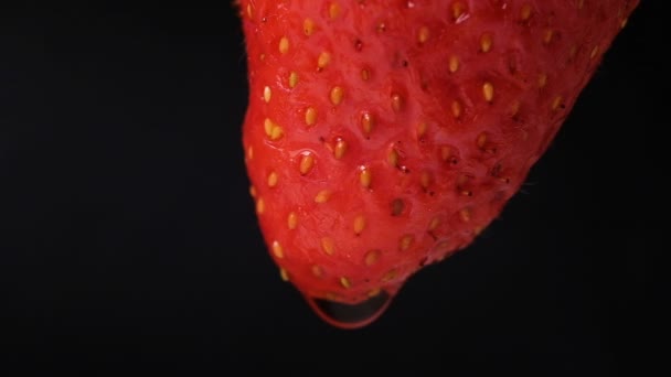 Gota de água flui para baixo um close-up de morango em um fundo preto, câmera lenta — Vídeo de Stock