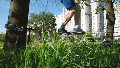 Genç yavaş yavaş şehir parkta çizgisinde adımları adam. Adam bakiyelere slackline, ağır çekim