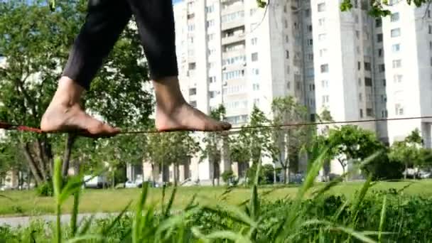 Menina europeia está andando em uma linha apertada em um parque da cidade. Mulher balanceando no slackline, close-up — Vídeo de Stock