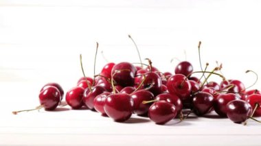 Kız beyaz bir arka planda olgun kiraz yalan bir tablo üzerine çilek bir plaka bırakır