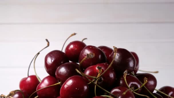 Рука кладет вишни на большую груду ягод на белом фоне — стоковое видео