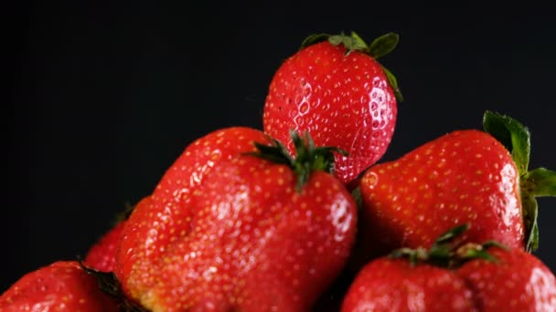 Man tar en jordgubbe på toppen av en stor hög på en mörk bakgrund, närbild — Stockvideo