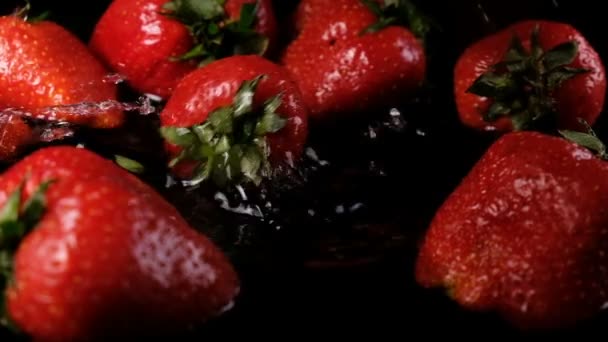 Erdbeere, die vor dunklem Hintergrund ins Wasser fällt, Zeitlupe — Stockvideo