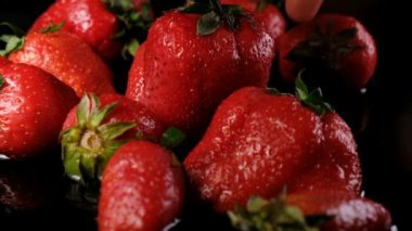 Kadın su koyu arka plan yakın çekim, ağır çekim üzerinde çilek alır