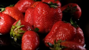 Kadın alır bir olgun sulu büyük çilek berry sudan karanlık bir arka plan üzerinde yakın çekim