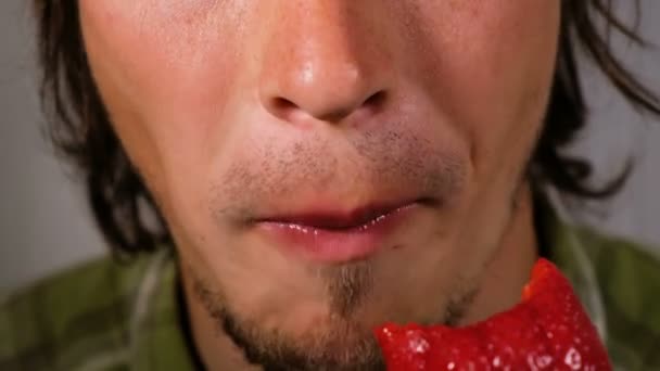 O homem come morangos maduros apetitosos close-up. Cara faminto mastiga uma grande baga madura com prazer — Vídeo de Stock