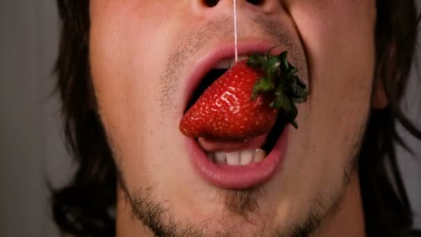 Strawberry and mouth close-up. Man is eating a berry with strings — Stock Video