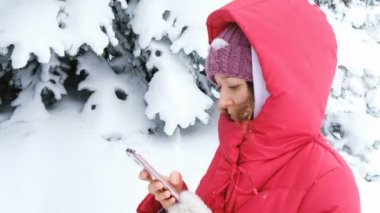 Kızı ormanda oynadı ve önemli haber hatırladım hızlı bir mesaj kız aşağı ceketli ve kafasındaki kar ile önemli konular hakkında yazıyor