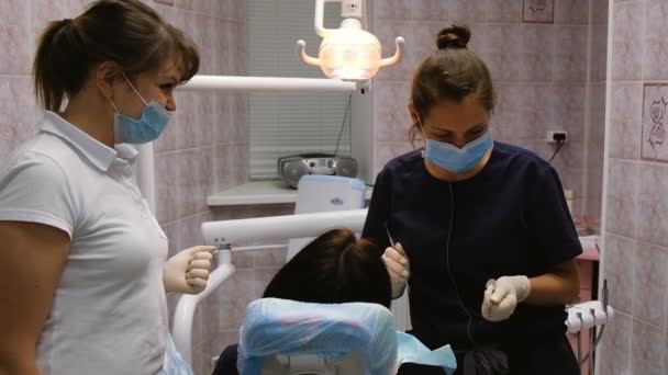 Dois jovens médicos de uma mulher dentista tratar um paciente em um consultório odontológico, câmera lenta — Vídeo de Stock