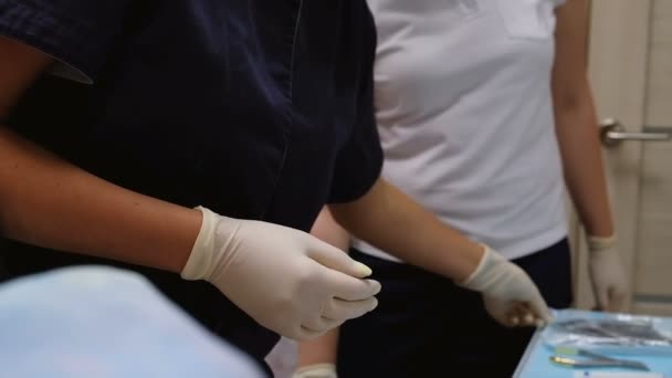 El dentista con guantes blancos de goma toma una herramienta con pinzas para apretar los frenos del sistema o quitar el diente . — Vídeo de stock