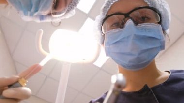 Gözlüklü diş hekimi hastanın eğildi ve dişlerini tedavi