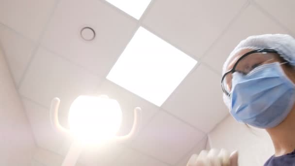 El dentista y el ayudante en las gafas se han inclinado sobre el paciente y tratan los dientes — Vídeo de stock