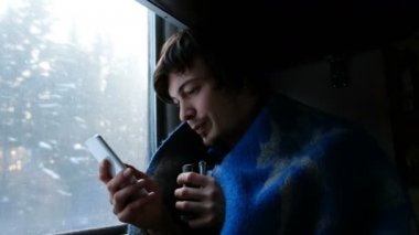 Bir tren seyahat bir ekose erkekte ve smartphone, 4 k kullanır.