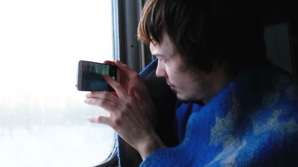 在地毯上的男人坐火车旅行 在电话里拍大自然的照片 相机从窗户上显示出窗外的景色 大自然通过火车的窗户 — 图库视频影像