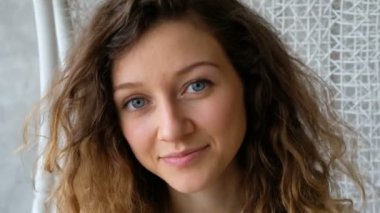 Güzel bir mavi gözlü kız portresi. Avrupalı genç bir Bayan evin lounge alanında bir salıncak üzerinde salıncak ve kameraya doğru görünüyor.