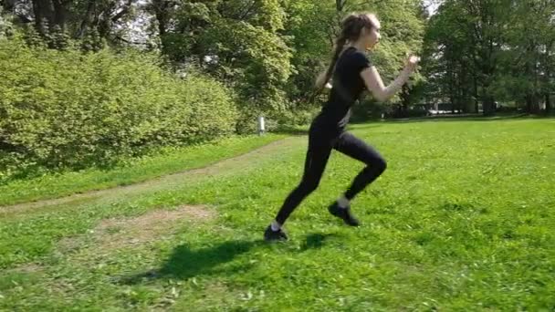 Молодая девушка с длинной косой бегает по парку. Молодая женщина бегает летом, замедленная съемка — стоковое видео